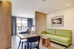 A modern hotel room with a wooden dining table, a green sofa, a small wooden side table, and a framed picture on the wall. - w Lovely Loft w Balcony in Santa B Rbara (Bogotá)