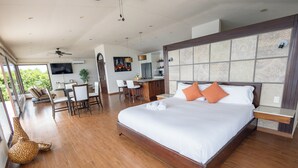 Un dormitorio amplio con una cama grande, una zona de comedor y una cocina al fondo.