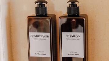 Two bottles of conditioner and shampoo from the Verona Collection, placed in a shelf.