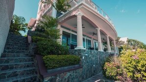 Un edificio de varios pisos con fachada de piedra, un balcón y una escalera que lleva a la entrada.