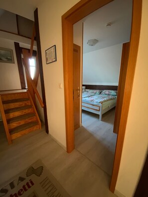 Ein Schlafzimmer mit einem Bett, einer Holztreppe und einer Tür zu einem anderen Raum.