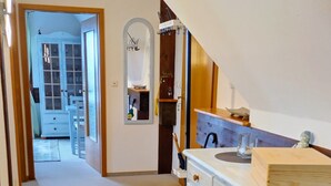 A hallway with a kitchen area, a staircase, and a dining room visible in the background. - Apartment 'Inselstern' with Balcony and Wi-Fi (Pellworm)