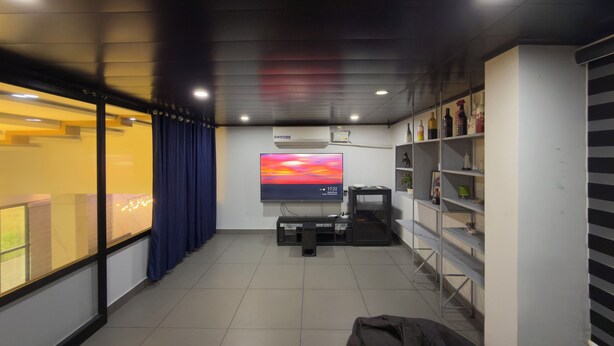 Una sala de estar moderna con un televisor de pantalla plana, una consola de videojuegos y una estantería.