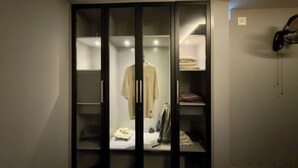 Un vestidor amplio con varios estantes y espacio para colgar, que contiene ropa doblada y una chaqueta colgada.
