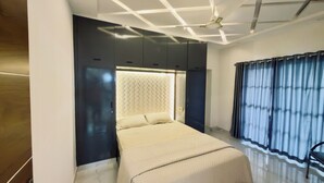 A modern bedroom with a large bed, built-in wardrobe, and a ceiling with geometric lighting.