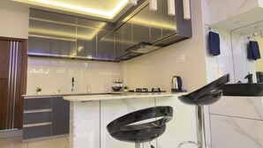 Una cocina moderna con electrodomésticos de acero inoxidable, encimera de mármol y una barra con taburetes.