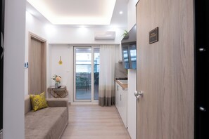 A modern apartment with a kitchenette, a sofa with a yellow cushion, a sliding glass door to a balcony, and a sign reading "Royal Penthouse 2". - Luxury Penthouse in Athens (Athens)