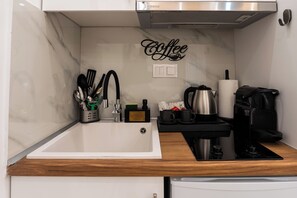 A compact kitchen with a marble backsplash, a coffee-themed wall decoration, a sink, and a coffee machine. - Luxury Penthouse in Athens (Athens)