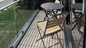 A balcony with a glass railing, a small round table, and two chairs.