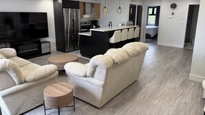 A modern living room with a large flat-screen TV, a sofa, and a coffee table.