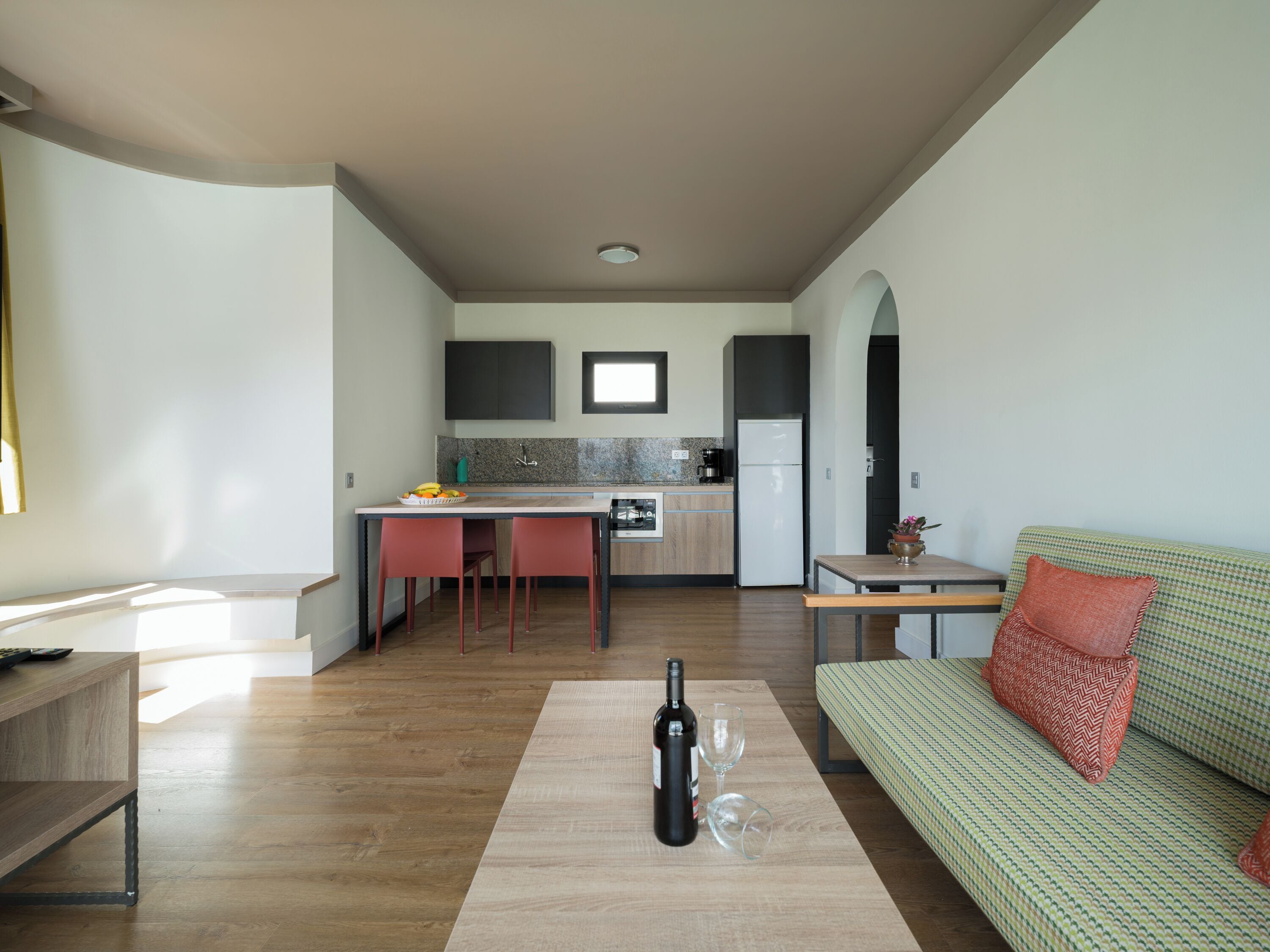 Une cuisine moderne avec un coin repas, un canapé et une bouteille de vin posée sur une table.