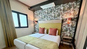 A double bed with a green throw, two red pillows, a headboard, and a wall with a tropical leaf pattern. - Servatur Doña Elvira Adults Only (Mogán)
