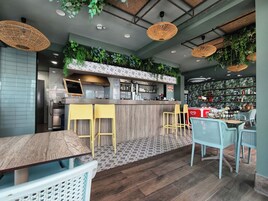 Ein modernes Café-Interieur mit Barbereich, Sitzgelegenheiten und einer mit Pflanzen verzierten Wand.