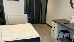 A bedroom with a bed, a desk, a chair, a radiator, a wardrobe, and a TV on the wall. - Motel like en suite room, own front door. Secure parking. 1 mile to crewkerne (Crewkerne)