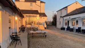 A courtyard with outdoor seating, a flower garden, and a building with a large window and a door. - Motel like en suite room, own front door. Secure parking. 1 mile to crewkerne (Crewkerne)