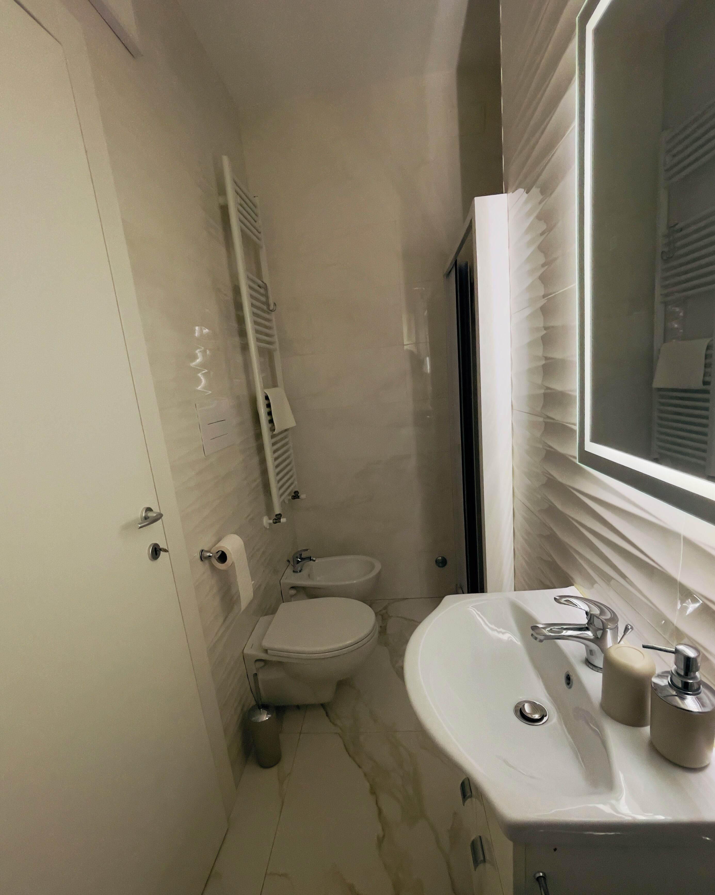 A compact bathroom with a toilet, bidet, and a sink with a mirror.