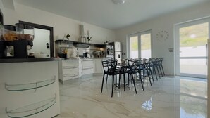 A modern kitchen with a dining area, featuring a marble floor, a built-in oven, and a large window providing natural light. - Beb Villa Real (Balvano)