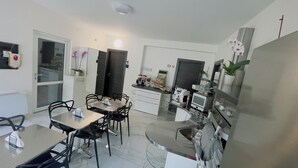 A modern kitchen with a dining area, equipped with a refrigerator, microwave, and coffee machine. - Beb Villa Real (Balvano)