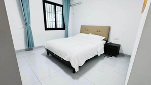 A bedroom with a bed, a nightstand, and a window with curtains.