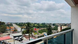 A view of a cityscape from a balcony with buildings, roads, and a distant tower.