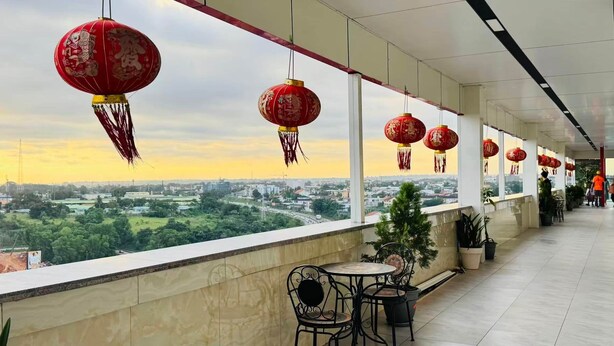 A balcony with red lanterns, a view of a cityscape, and outdoor seating.