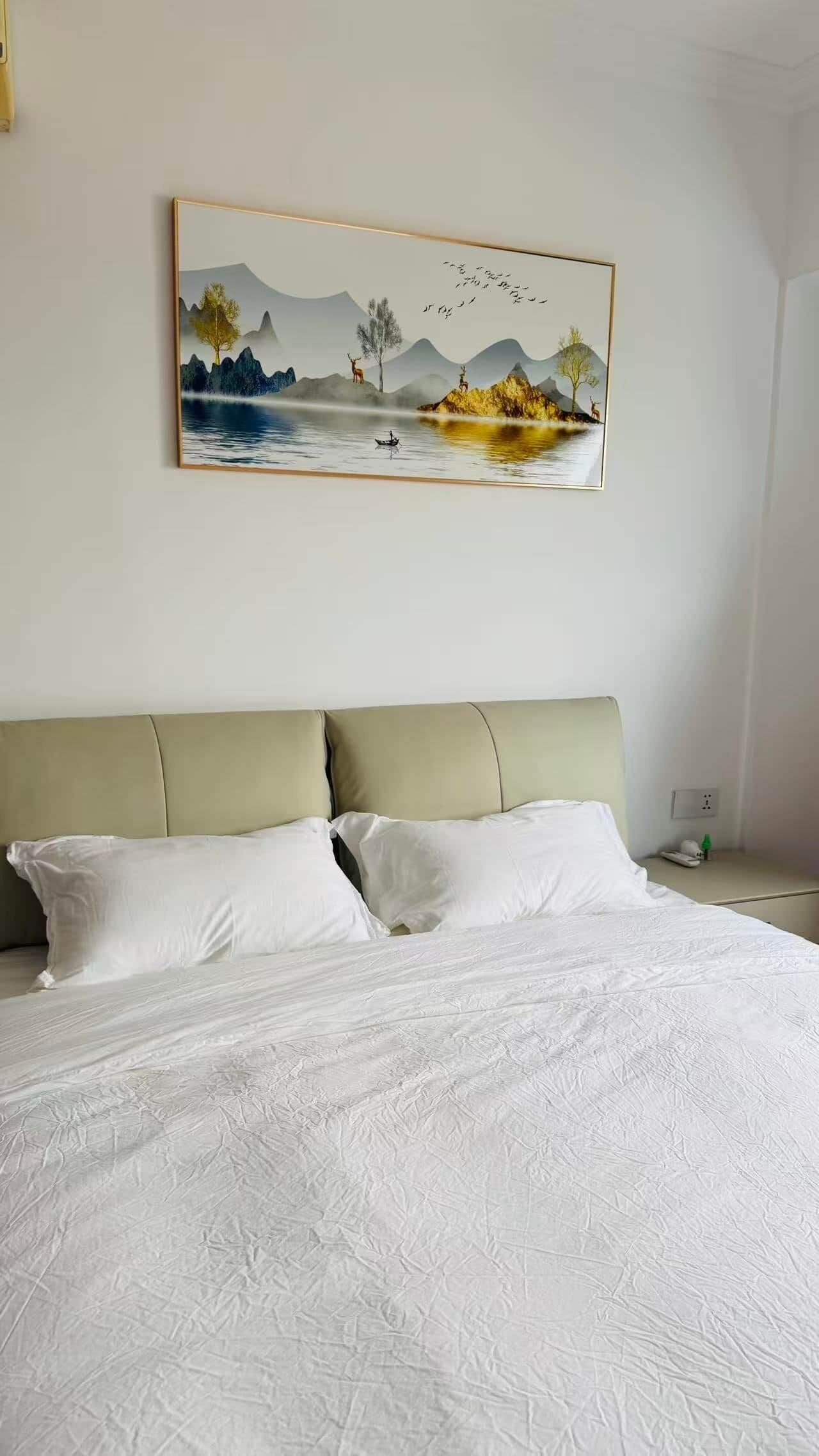 A bedroom with a bed, a headboard, and a painting of a landscape.