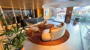 A modern lobby with a reception desk, seating area, and a view of the street. - W Tambaú Apart Hotel (João Pessoa)