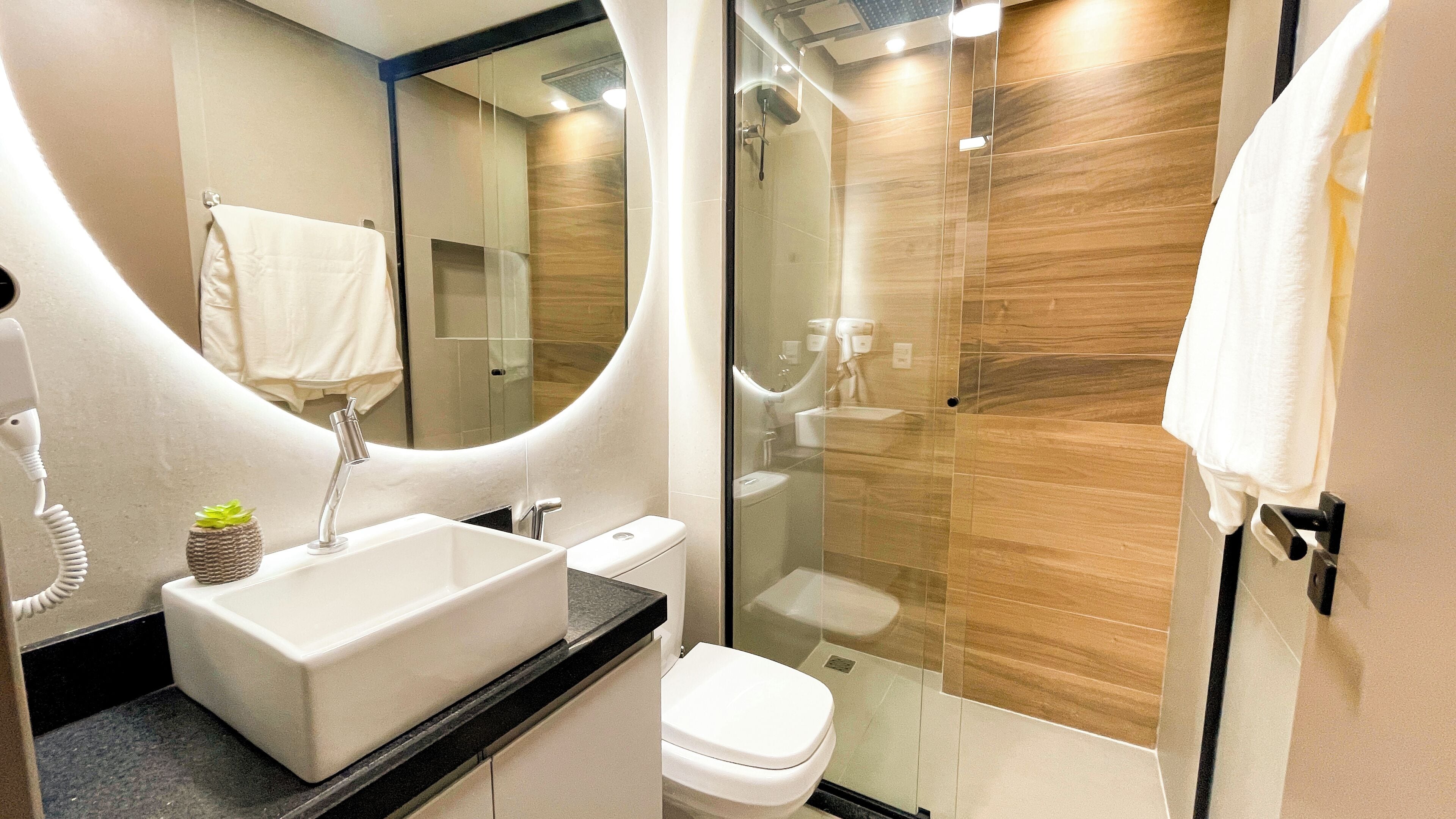 Een moderne badkamer met een grote spiegel, een wastafel, toilet en douche.