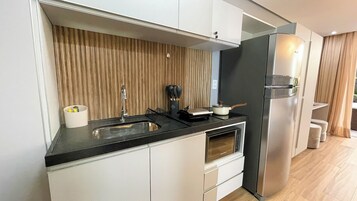 Una cocina compacta con encimera negra, electrodomésticos de acero inoxidable y un salpicadero de madera.