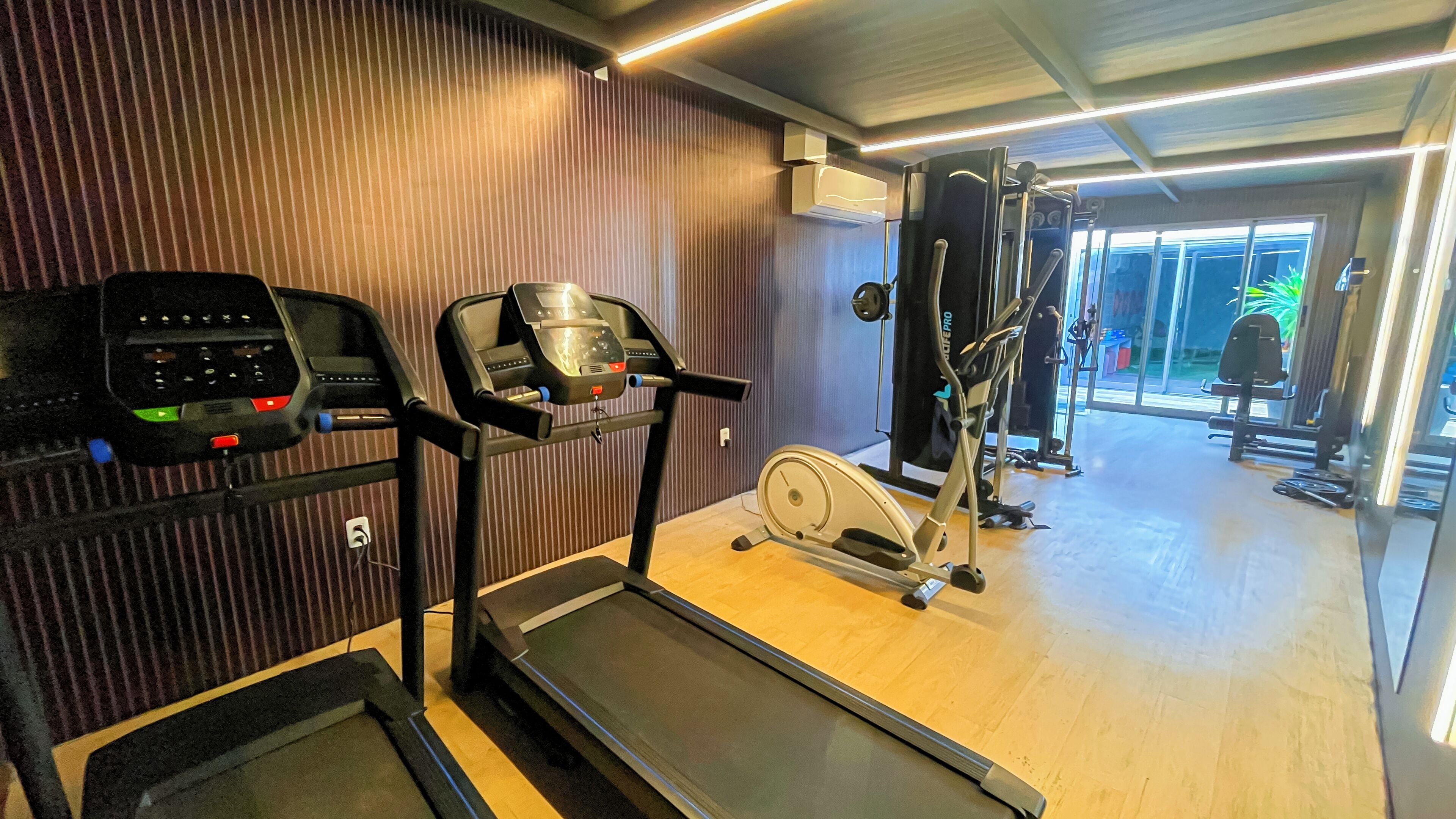Ein Fitnessraum mit Laufbändern, Crosstrainern und Kraftgeräten.