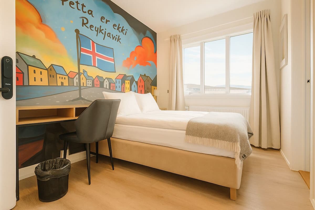 A bedroom with a bed, a desk, and a chair. There is a window with curtains and a view of the sky.