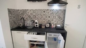 A compact kitchen with a black countertop, white cabinets, and patterned backsplash. - Sirocco - House of Jana (Quartu Sant'Elena)