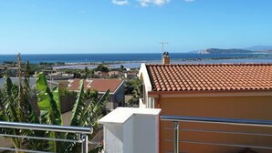 A coastal view with a clear sky, a building with a tiled roof, and a distant body of water. - Sirocco - House of Jana (Quartu Sant'Elena)