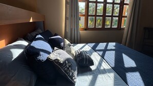 A bedroom with a bed, curtains, and a window with a view of palm trees. - Rancho Tortuga Fuertevali (Acajutla)