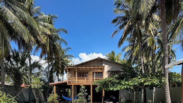A swimming pool with a wooden deck and a house in the background. - Rancho Tortuga Fuertevali (Acajutla)