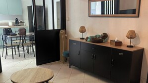 A modern living room with a round wooden table, a black cabinet, and a large mirror on the wall. - Beautiful studio (Volx)