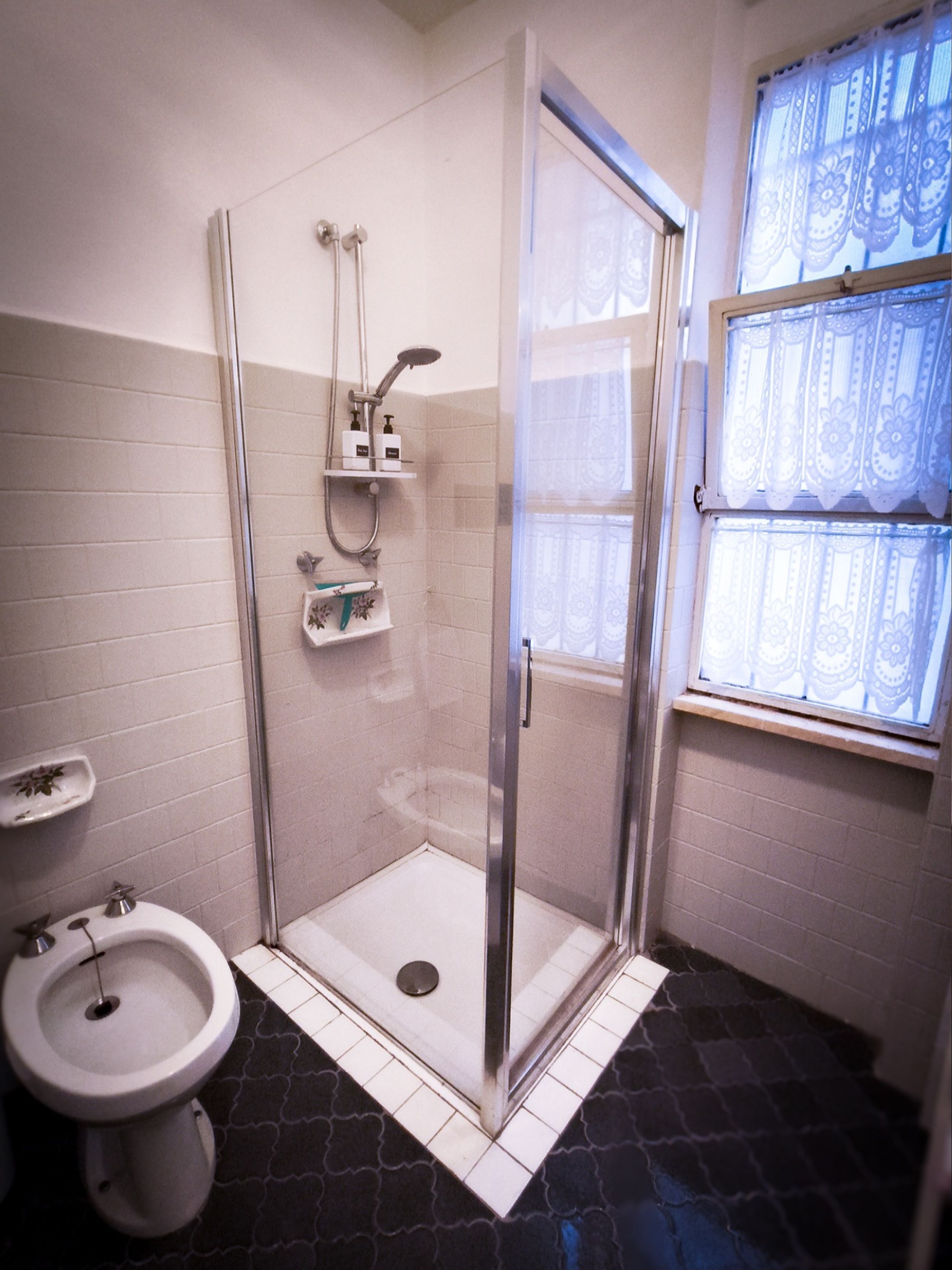 A bathroom with a shower, toilet, and bidet.
