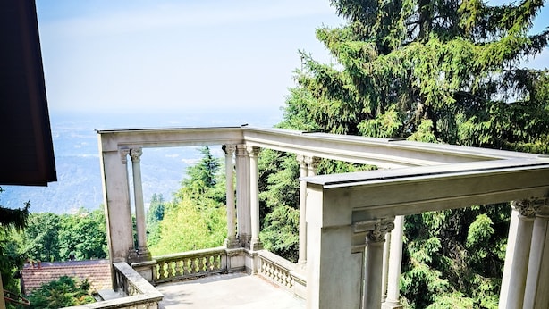 A covered outdoor area with columns, potted plants, and a view of the landscape. - Villa Scurati (Brunate)