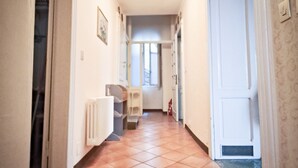 A hallway with a tiled floor, a radiator, a door, and a light fixture. - Villa Scurati (Brunate)