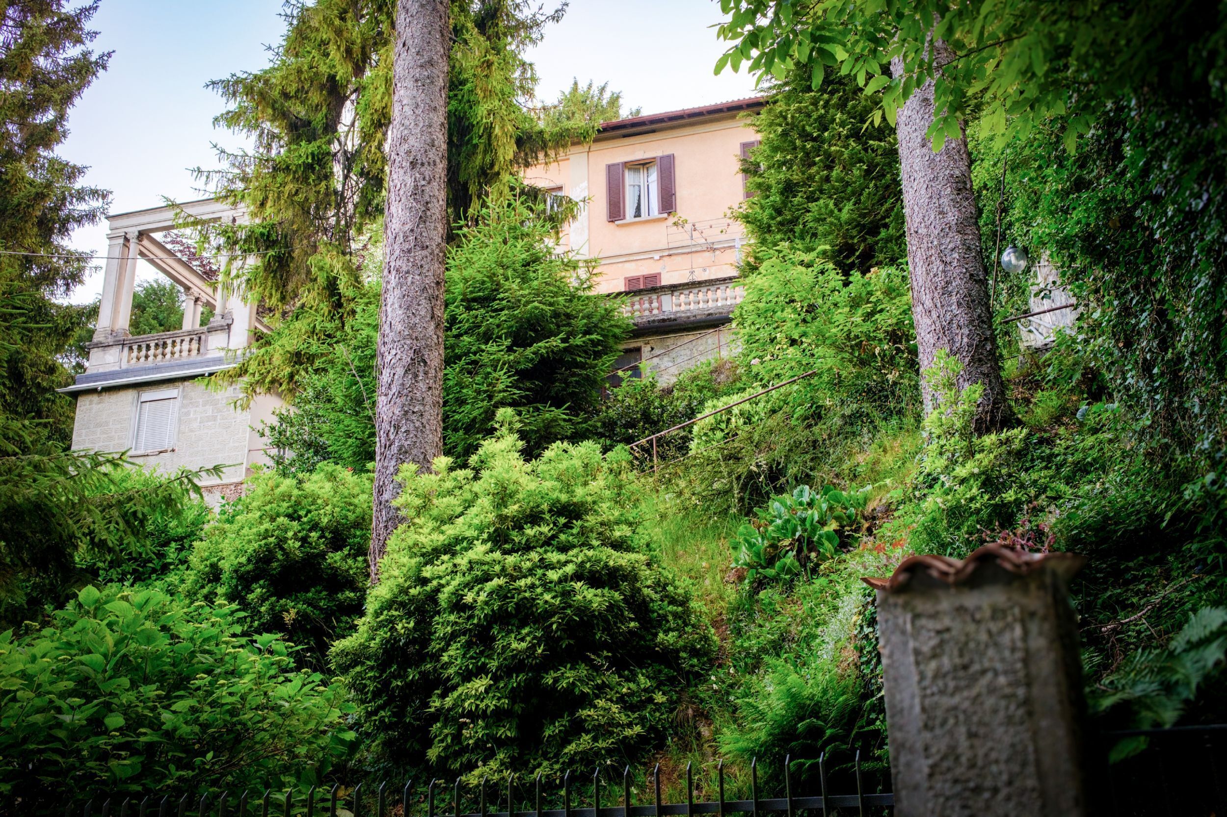 Un edificio immerso nel verde, con struttura in pietra e un balcone.