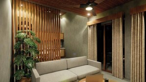 Un soggiorno moderno con un divano, una pianta in vaso, una parete divisoria in legno e una ventola a soffitto.