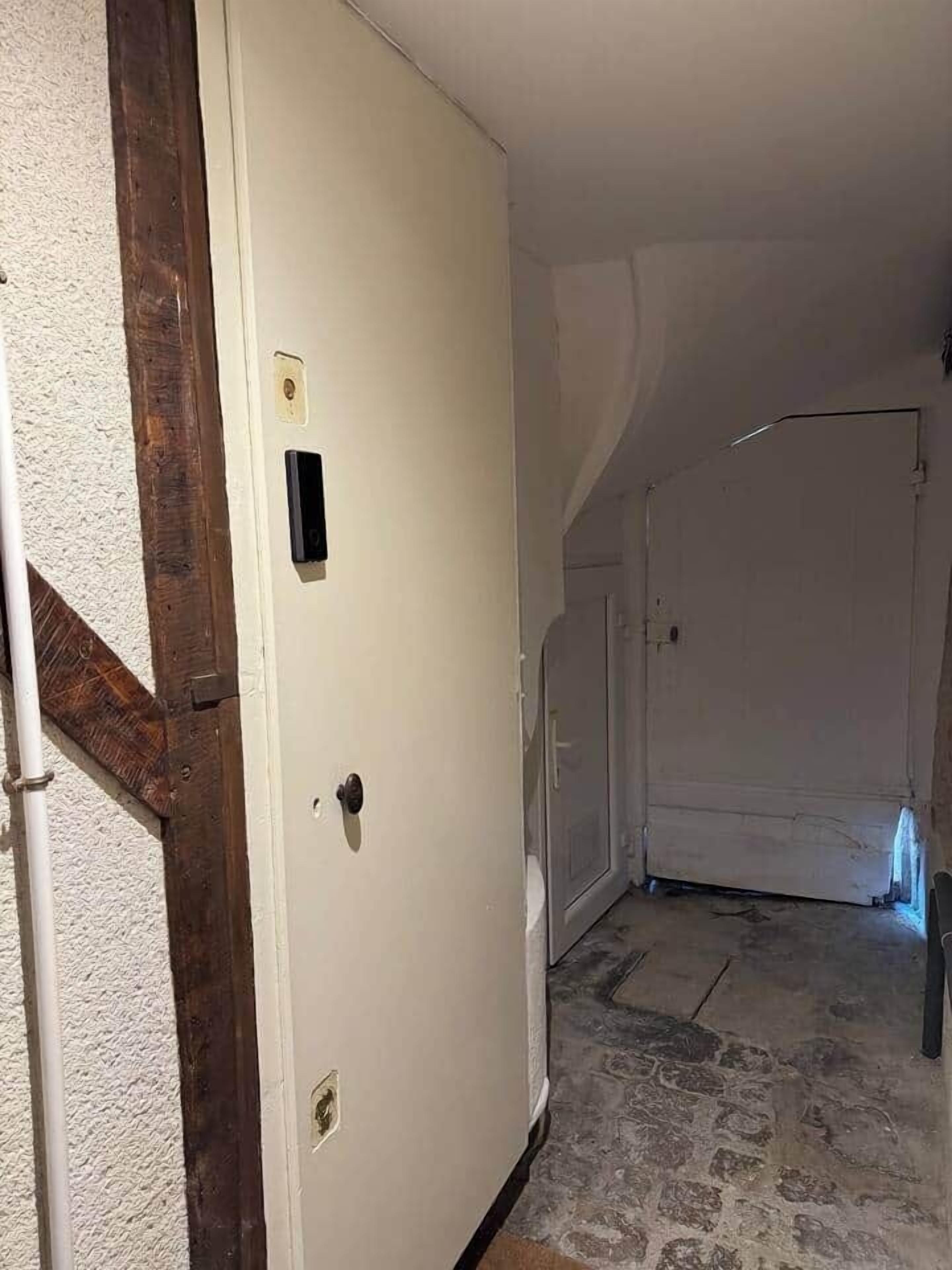A room with a white door, a wooden beam, and a tiled floor.
