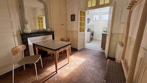 Une pièce dotée d’un sol carrelé en forme d’hexagone, d’une table en bois avec deux chaises, d’un grand miroir et d’une porte donnant sur une autre pièce.