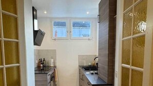 Une cuisine étroite avec des meubles de rangement en bois, un plan de travail et une fenêtre au-dessus de l’évier.