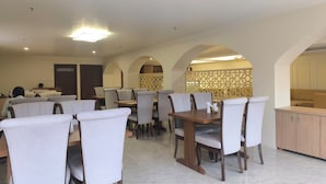 A restaurant with tables and chairs, a washroom, and a decorative partition. - The Imperia (Guwahati)