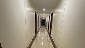 A long, narrow hallway with a shiny floor and white walls. - The Imperia (Guwahati)