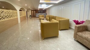 A spacious lobby with a marble floor, yellow sofas, and a reception desk. - The Imperia (Guwahati)