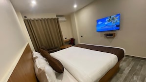 A hotel room with a bed, a television mounted on the wall, and a window with curtains. - The Imperia (Guwahati)