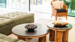 A modern living room with a tufted sofa, a round wooden coffee table, and a wicker chair. - Beachside on Pacific (Mission Beach)