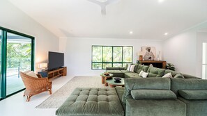 A modern living room with a sectional sofa, a television, and a large window. - Beachside on Pacific (Mission Beach)